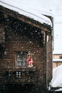 christmas decoration on wooden cottage balcony during heavy snowfall