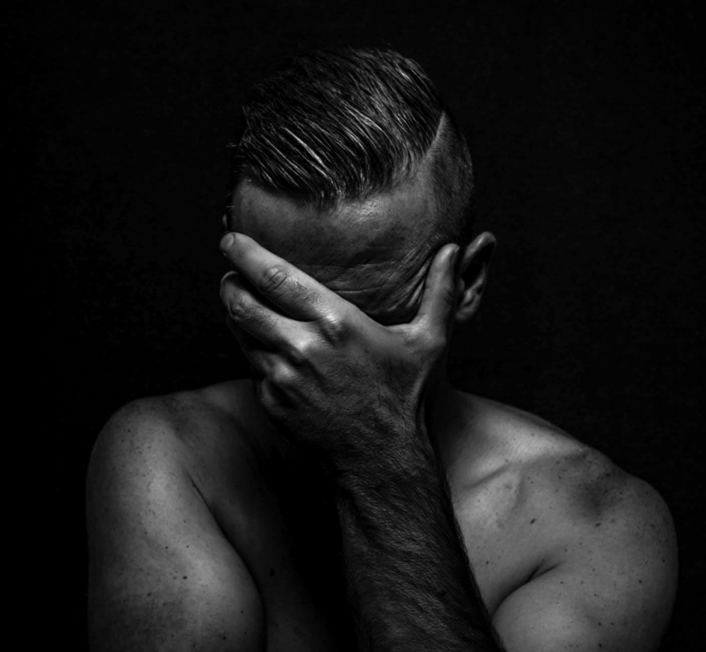 anonymous depressed shirtless man with modern hairstyle on black background
