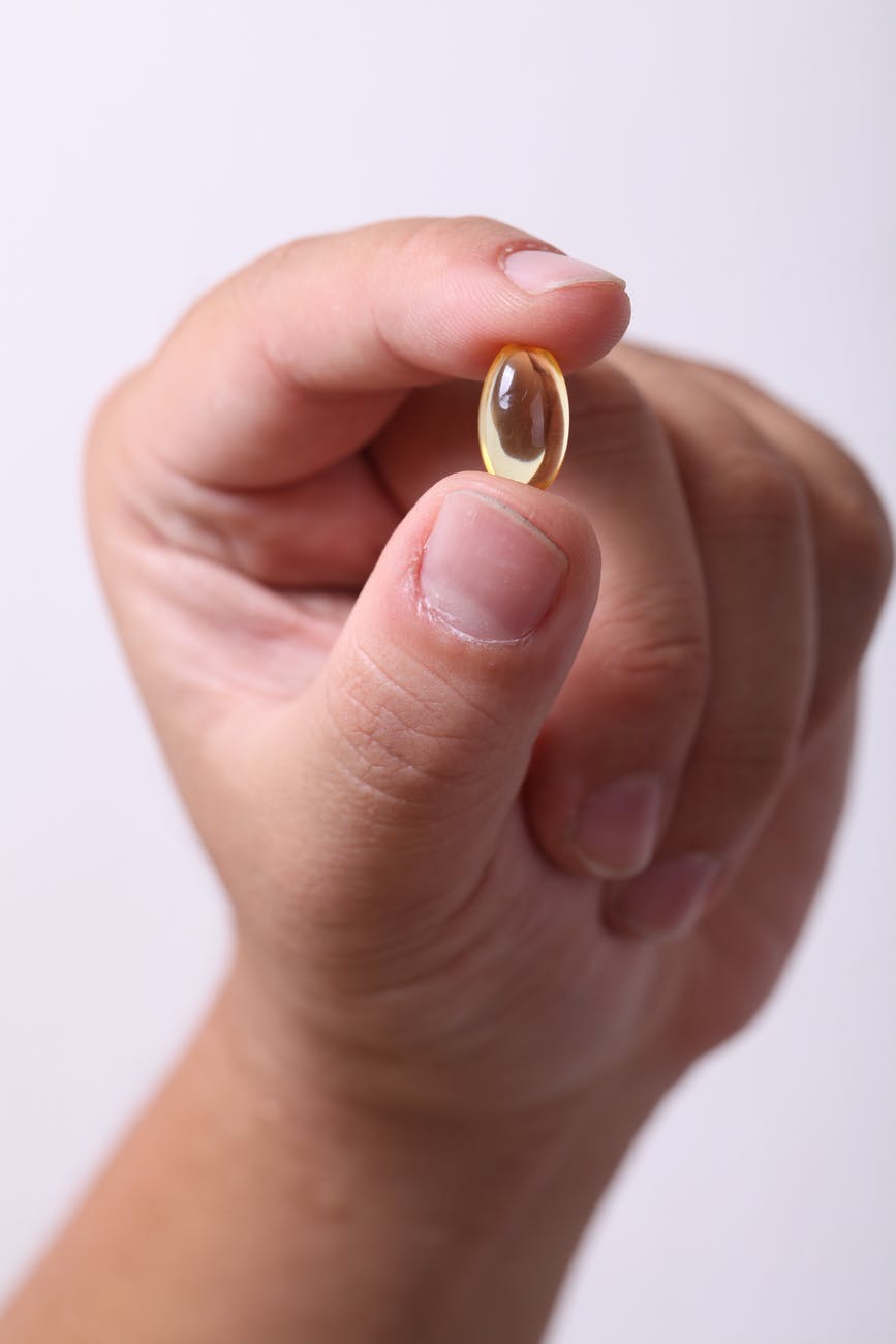 person holding oval clear capsule