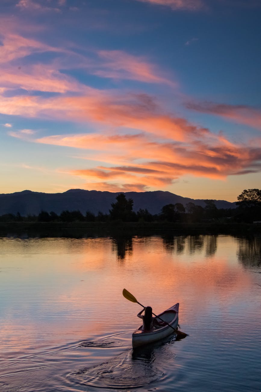 photo of person riding kayak during dawn