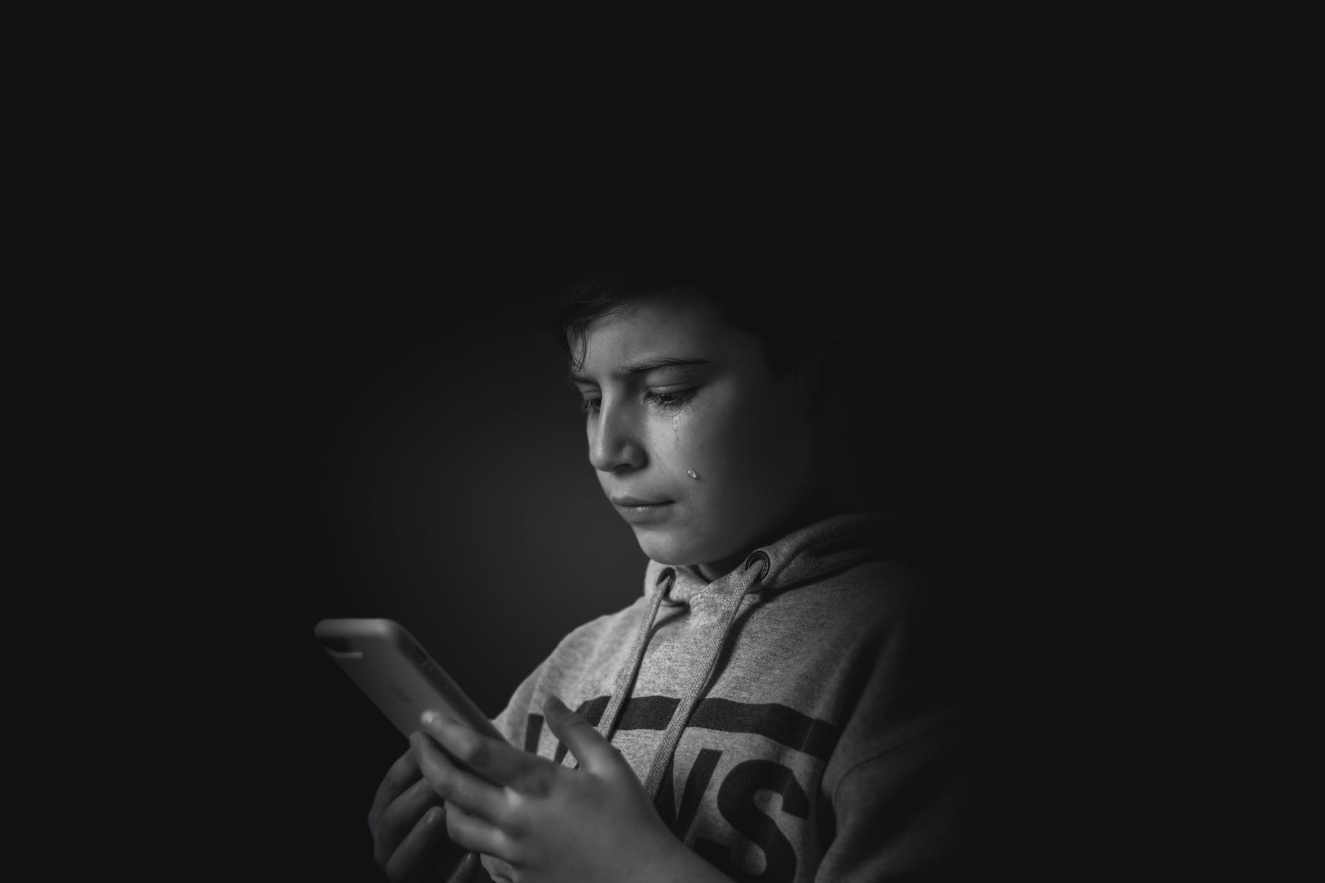 grayscale photo of boy holding smartphone