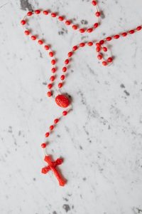 red rosary on white surface