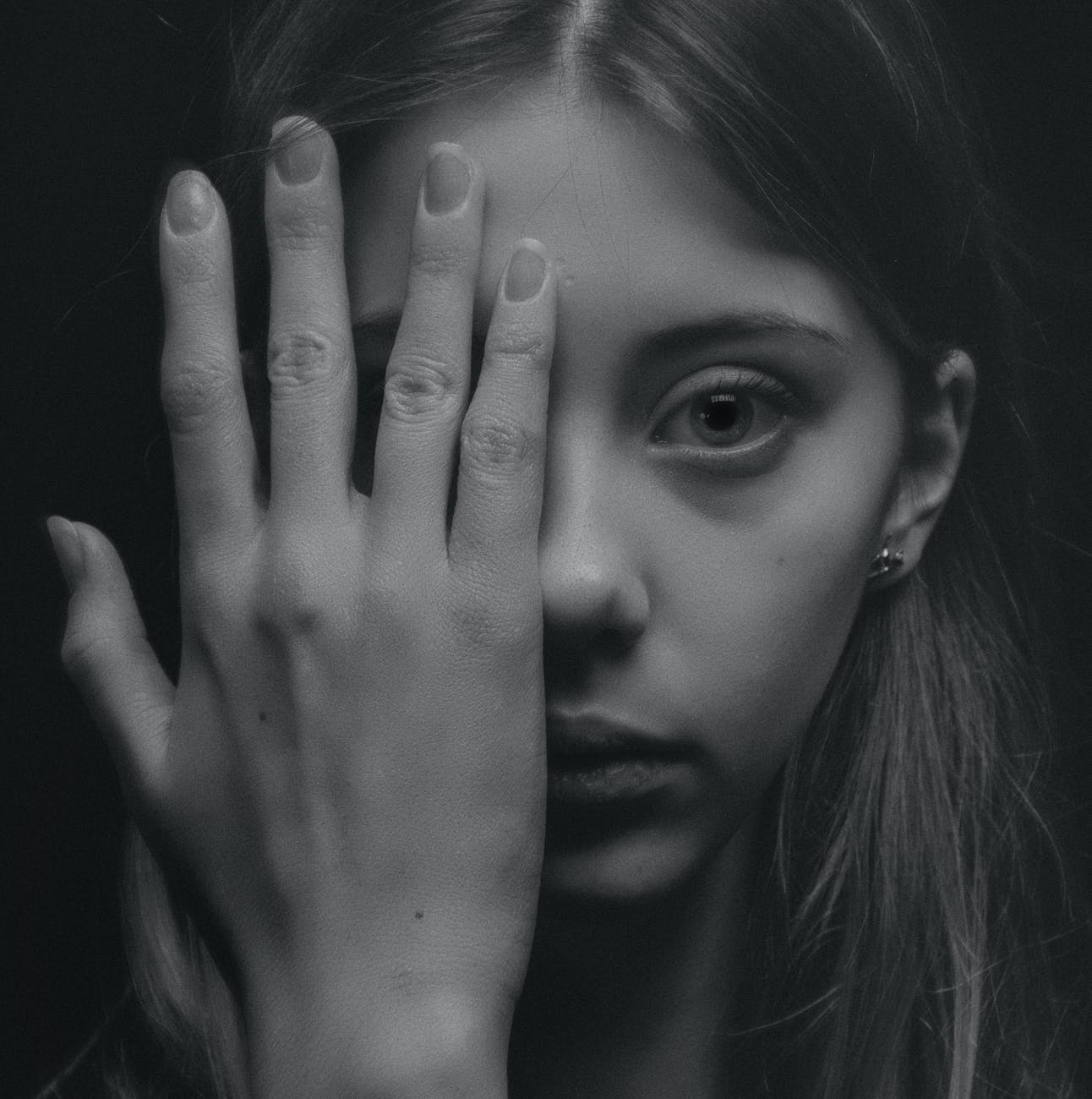 grayscale photo of woman covering her face by her hand
