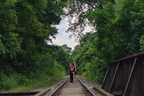 man and woman dancing on railroad tracks