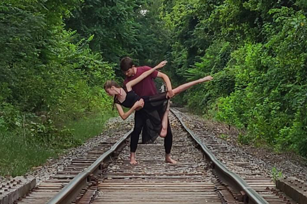 man and woman dancing on railroad tracks