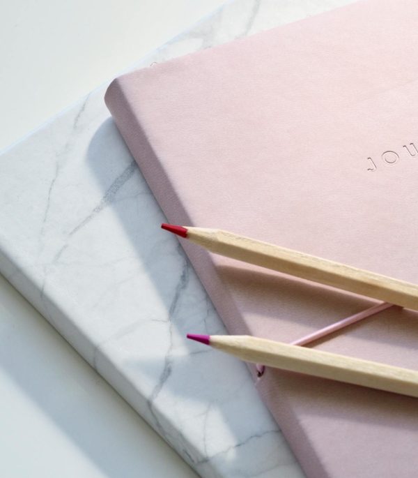 closeup photo of journal book and pencils